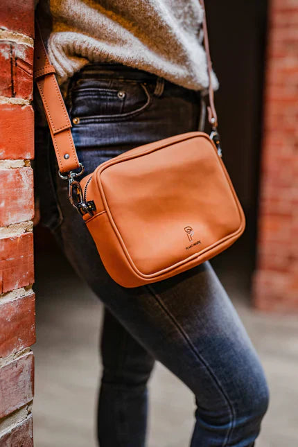 Plant Inside vegan crossbody bag worn over the shoulder, showing logo, strap and metal clasps – handcrafted sustainable design made to last