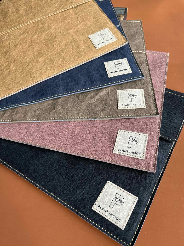A fan of Plant Inside’s vegan laptop cases in various colors held like playing cards – showcasing slim, stylish, and sustainable design made from Washpapa®