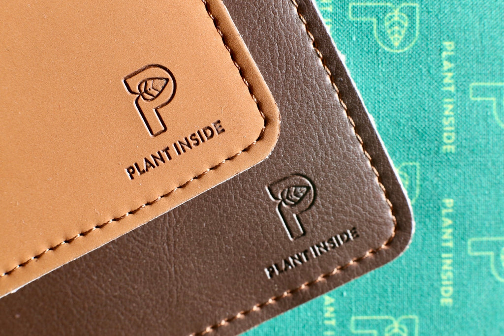 Close-up of two vegan wallets in camel nubuck and brown matt with visible stitching and embossed Plant Inside logo on green crossbody lining – symbol of timeless design and craftsmanship